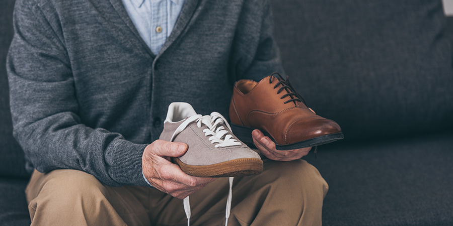 Man Holding Classic And Modern Shoes
