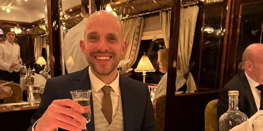 James holds his drink while sitting in the dining car of the Venice Simplon-Orient-Express. 