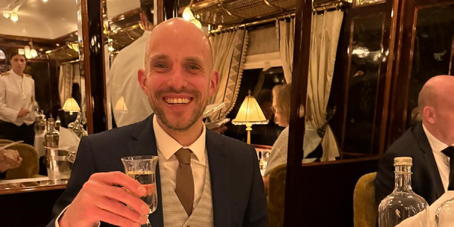 James holds his drink while sitting in the dining car of the Venice Simplon-Orient-Express. 