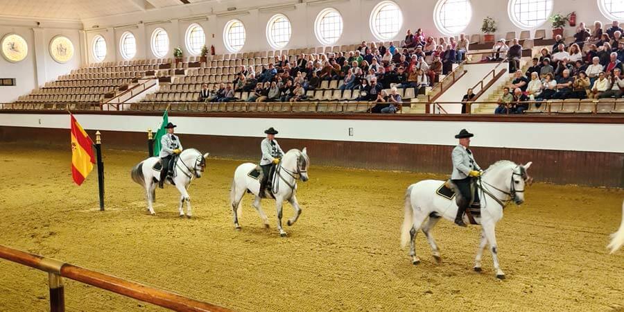 A cultural horse dancing performance features three white horses.