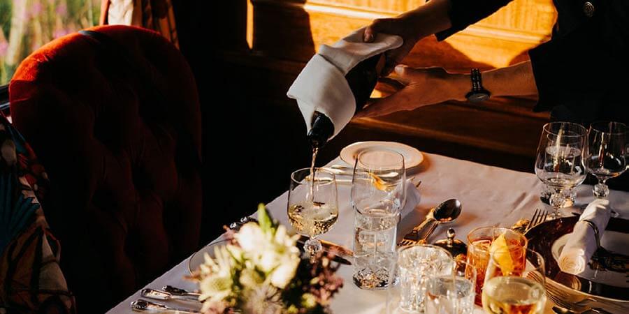Staff onboard the Royal Scotsman serve drinks with the evening meal. 