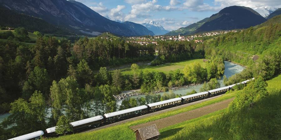 The Venice Simplon-Orient-Express travels through lush green scenery. 
