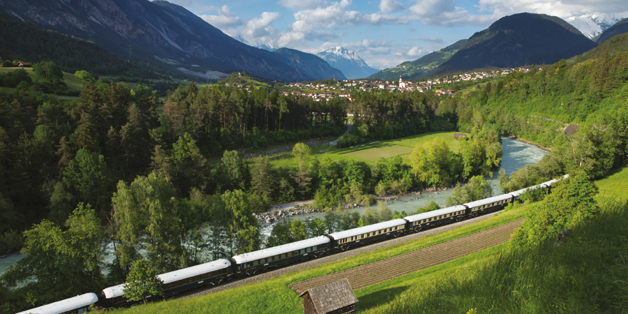 The Venice Simplon-Orient-Express travels through lush green scenery.